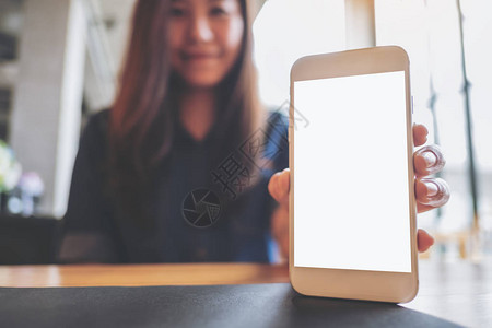 一位美丽的亚洲女在咖啡馆用空白屏幕装上白色手机的迷彩图像图片
