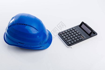 白色桌子上的蓝色安全帽和计算器图片
