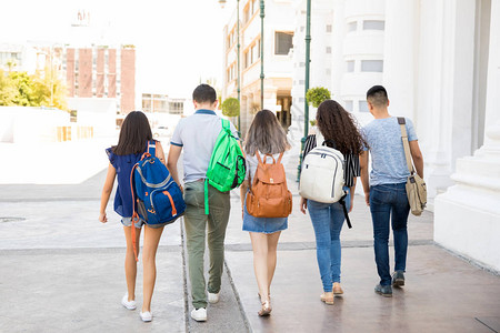 5名十几岁的男孩和女孩带着书包在市街上走出图片
