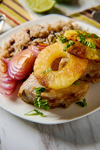 古巴菠萝猪排加传统黑豆米烤红洋葱和油炸白薯片的图片
