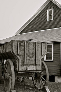 一辆装有木轮的旧粮食车停在一间农场粮仓前面图片