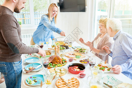 感恩回馈活动专注于微笑的年轻女在现代公寓的节日庆祝活动中提供食背景