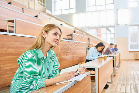 国际人群坐在现代大学报告厅的不同桌子上背景图片