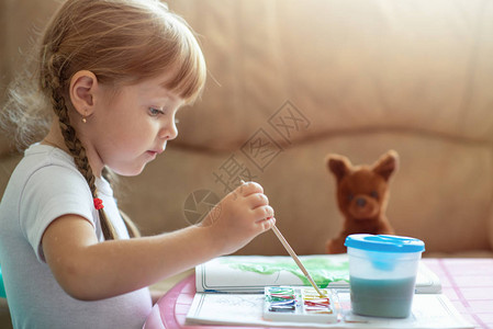 四岁小四岁的乌克兰女孩通过坐在桌边的油漆来涂彩形图片