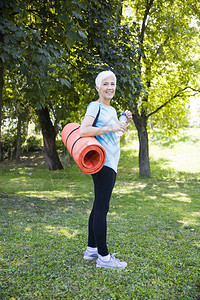 年长妇女在公园里背着一个健身垫图片