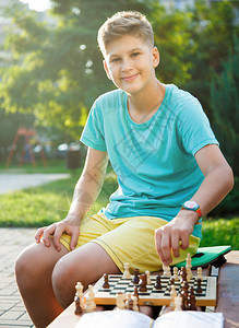 穿着绿色T恤的可爱小男孩在棋盘上运动图片