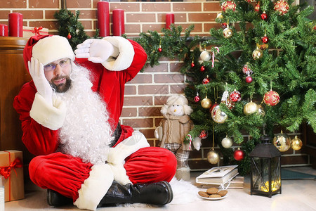 圣诞老人和礼物坐在圣诞树旁图片