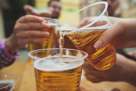 在户外酒吧或酒吧享受和喝啤酒的一群朋友图片