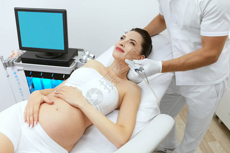 孕妇在美容诊所接受面部美容治疗做痤疮疤痕皮肤磨皮治疗的美容图片