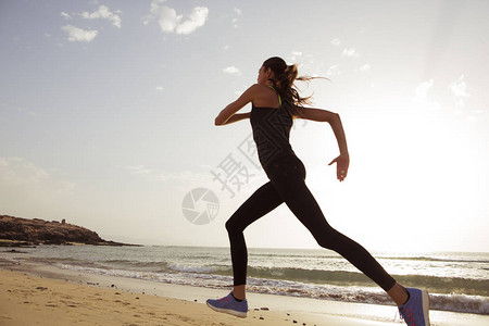 早上在沙滩上跑步的年轻运动女背景图片