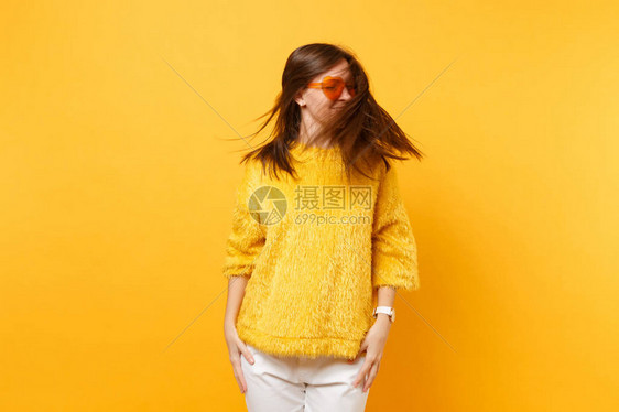 穿着毛衣和心形橙色眼镜的有趣年轻女子在工作室里鬼混图片