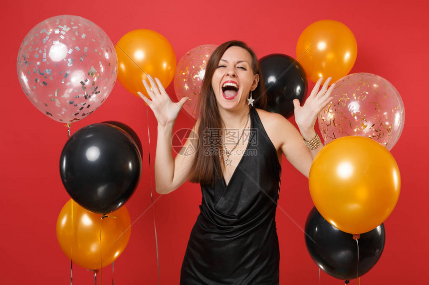 快乐的年轻女孩穿着黑色小礼服尖叫着庆祝在鲜红色的气球上张开双手圣瓦伦丁节妇女节新年快乐生日模拟图片