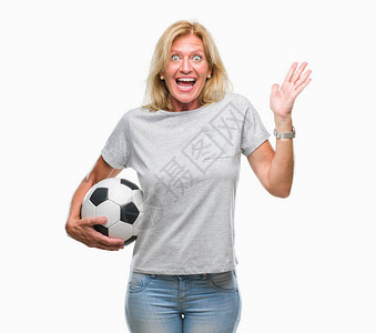 中年金发女子在孤立的背景下拿着足球非常高兴和奋图片