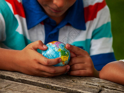 小朋友礼让一个拥有世界球或地球星的男孩在他的手背景