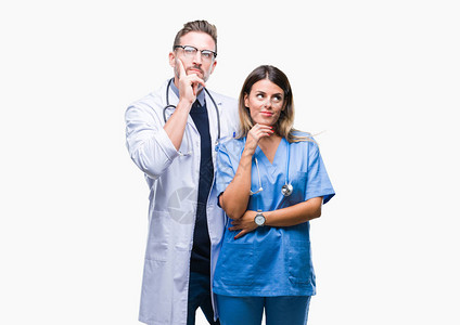 一对年轻的医生和外科医生在孤立的背景下用手托着下巴思考问题背景图片