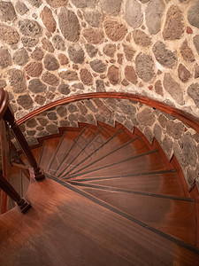 从楼下看的螺旋楼梯小木台阶和石墙内景图片