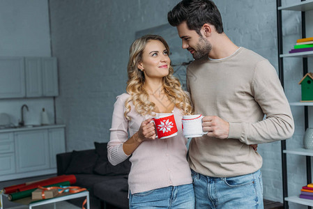 和茶杯连在一起的情侣在家里互相看对方圣诞节的概图片