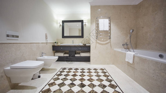 现代风格的漂亮浴室配有灰色瓷砖墙有一个带玻璃隔断的白色浴缸淋浴间镜子水槽马桶和坐图片