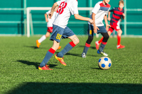 足球队身穿红色蓝色白色服的男孩在绿地上踢足球男孩运球运球技巧团队游戏训练积极生活方式爱好背景图片