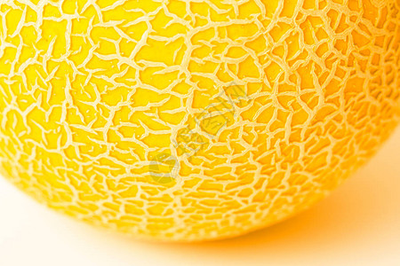 白色表面上的一块圆形黄色瓜质地瓜皮特写圆形视图作为瓜纹理浅景深图片