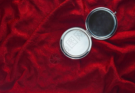 红色丝绸背景的迷你镜子女人化妆袋里的东图片