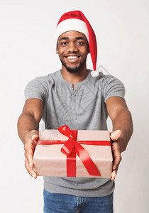圣诞礼物送服务以圣诞帽子赠礼盒白色工作室背景为圣塔帽微笑的非洲图片
