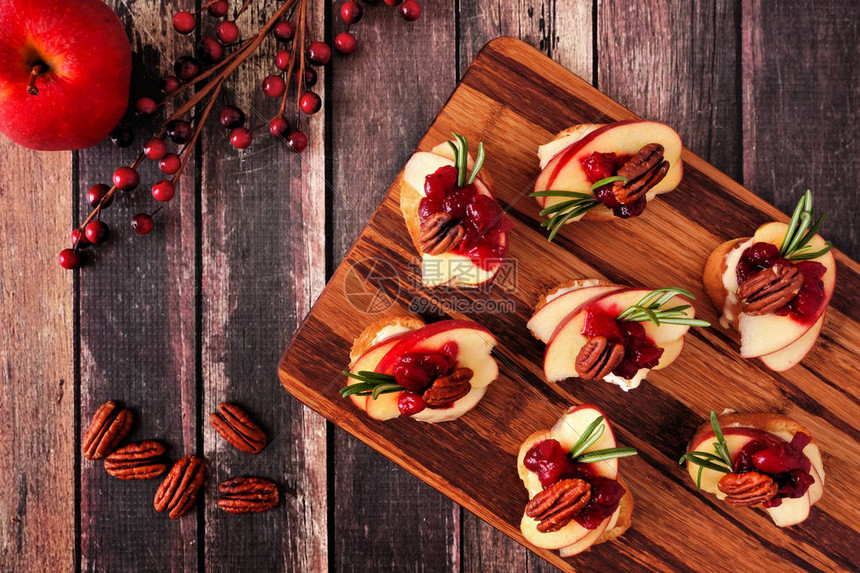 克罗斯蒂尼开胃菜有苹果红莓树莓和核桃在木盘上的图片