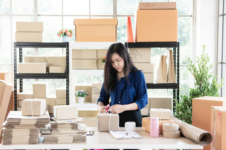 企业服务年轻漂亮的亚洲女人站在几个箱子中间检查包裹背景