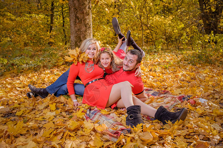 美丽的年轻家庭在阳光明媚的温暖秋天格子上玩得开心幸福的家庭关系的概念图片