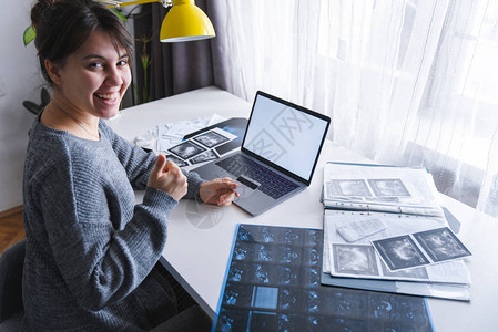 坐在家中的妇女带白屏的笔记本电脑桌子上的药品文件医疗保险图片