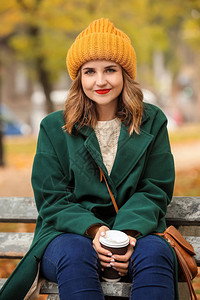 美丽的年轻女子秋天公园的木板凳背景图片