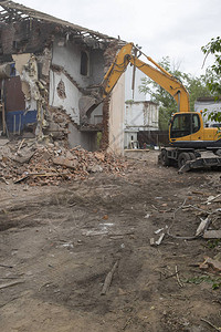 用一桶挖掘机摧毁旧建筑的墙壁和清理建筑垃圾图片