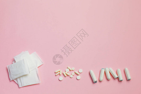 粉红色背景上的卫生巾卫生棉条和药丸背景图片