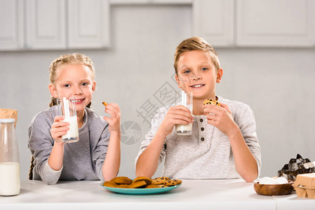 儿童在厨房餐桌边吃饼干和喝牛图片
