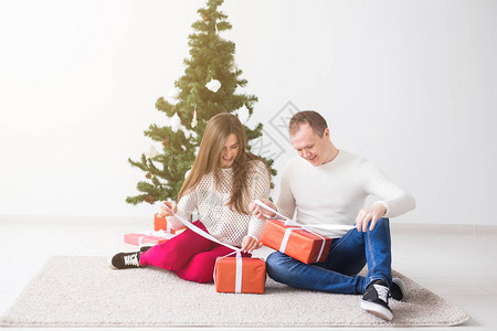 假期和圣诞节概念微笑着现代年轻夫妇开圣诞礼图片