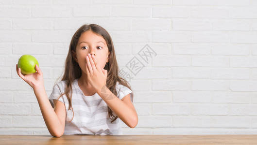 坐在桌上吃着新鲜绿苹果盖面的年轻西班牙小孩图片