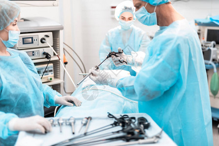 戴着无菌手套的医生将腹腔镜套管针连接到手术剪刀上的裁剪肖像背景图片