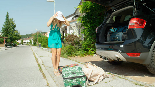 年轻女子在她所有的行李从停在她家门前的黑色SUV上掉下来后抓住了她的头刚度假回来的白种女孩打开后备箱图片