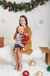 白种人母亲带着小男孩坐在木凳上拥抱庆祝圣诞节或新年轻女子与她的孩子儿在工作室里与图片
