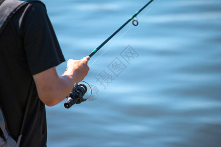 男人用鱼竿钓鱼特写图片