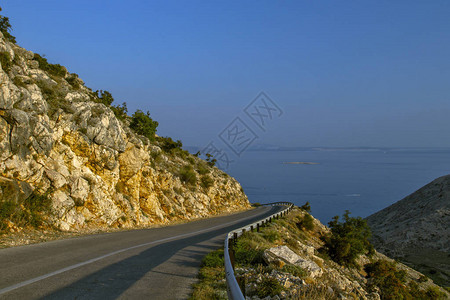 性感曲线美丽的山路风景与蓝天和附近的海岸线景观背景