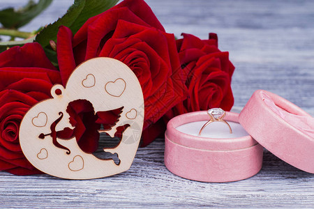 与玫瑰和金戒指的浪漫背景订婚戒指盒红玫瑰和木心图片