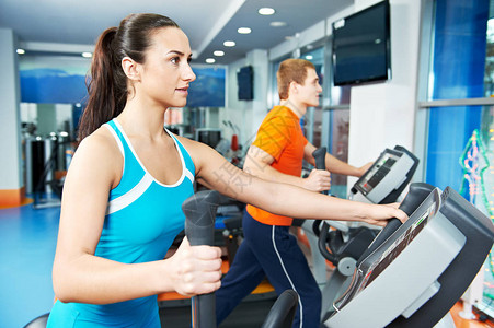 在健身房进行有氧训练男女在运动俱乐部的交叉训练机上背景图片