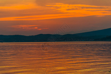 有夕阳的天空和地平线上的山脉的湖图片