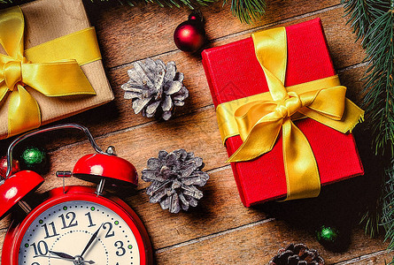 圣诞礼物盒和小闹钟靠近木制桌边松树图片