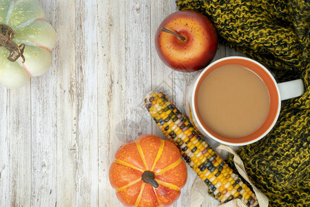 舒适的秋天背景与咖啡杯印度玉米南瓜苹果和温暖的毯子木材背景图片