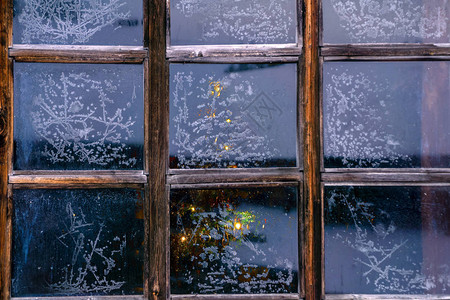 鲜艳的圣诞树在冰霜状的冰冻玻璃窗玻璃后图片