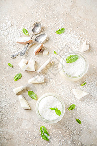纯素甜食玻璃罐装椰子奶冻甜点椰子片和薄荷叶浅色混凝土石图片