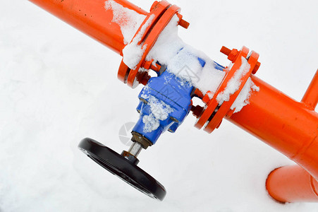 工业切断调节保护管件用于在冬季白雪背景下打开关闭带有法兰螺柱螺母的铁橙色金属背景图片