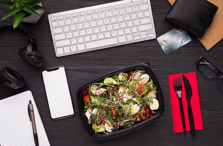 没有时间放午餐休息时间健康外送沙拉在工作场所顶视图电话屏图片